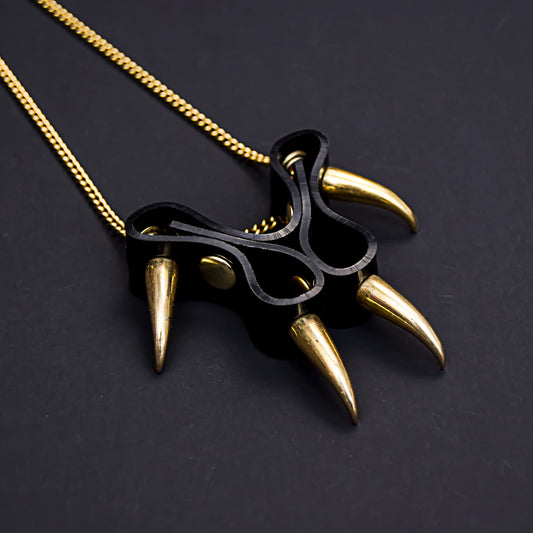 Close-up of a gothic black PVC cat paw pendant necklace, with gold hardware.