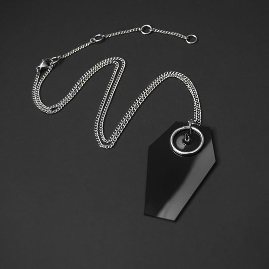 Gothic-style necklace featuring a black PVC coffin-shaped pendant with a silver spike and O-ring, suspended from an adjustable stainless steel chain.