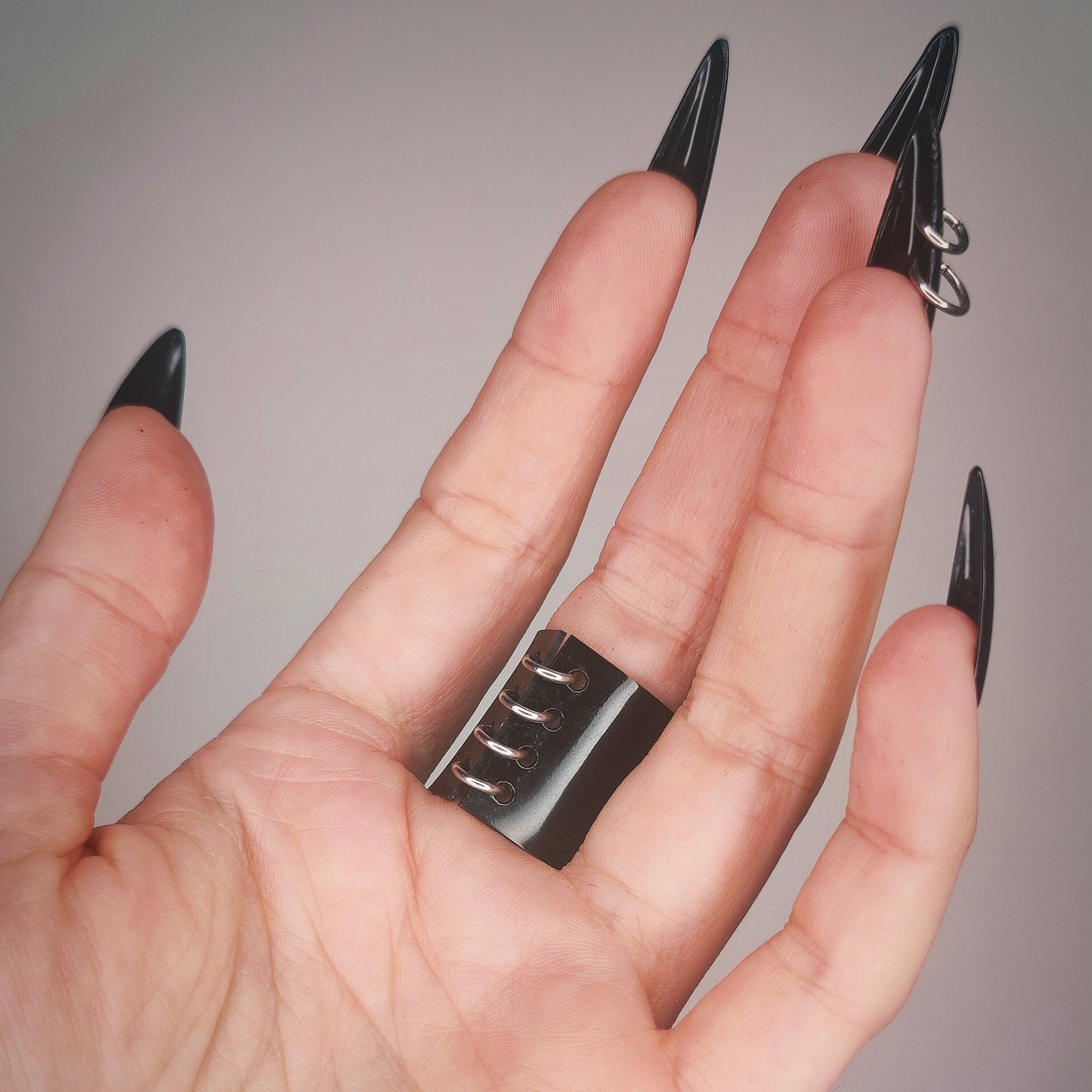 Underside of gothic gloss black PVC ring, with a row of jump rings.