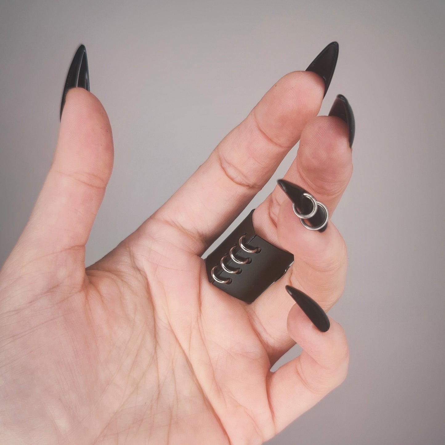 Underside of gothic matte black PVC ring, with a row of jump rings.