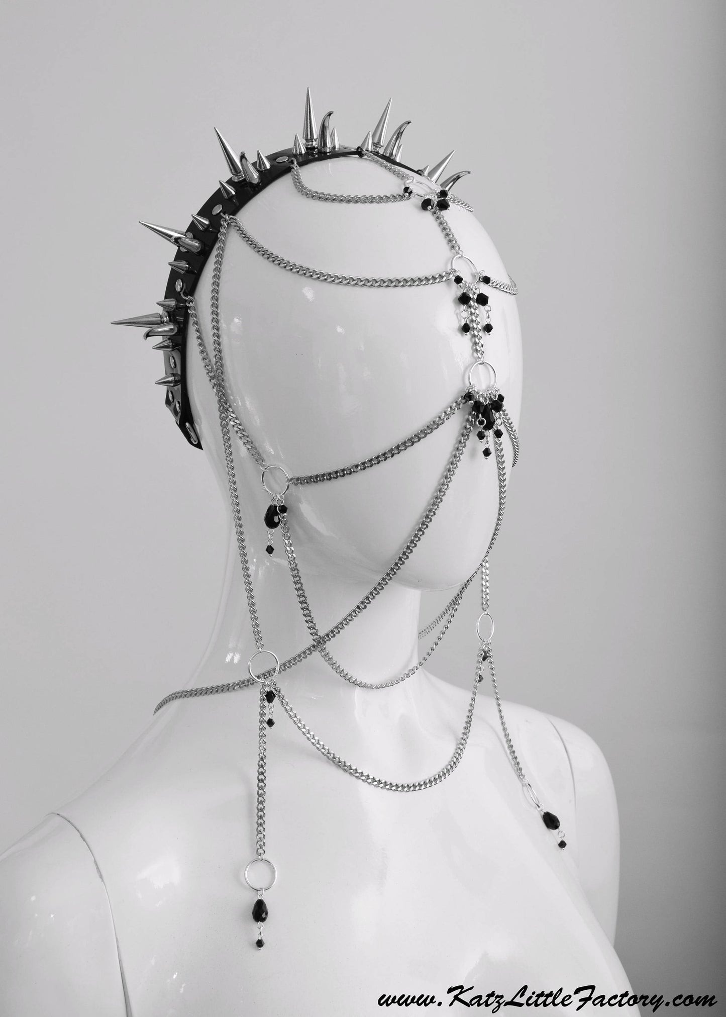 Profile of elaborate gothic headdress with a black PVC headband, clusters of spikes, and stainless steel chains and black glass beads face jewellery.