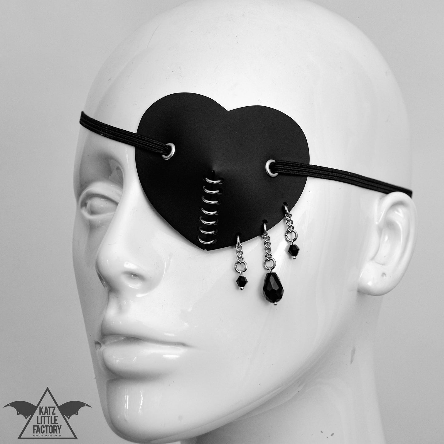 Black eye patch on a mannequin, with three droplets of beads
