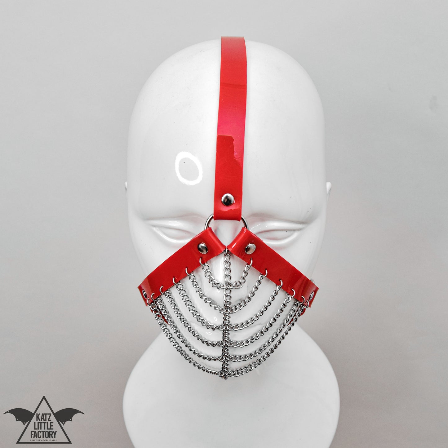Top down view of a gothic red PVC muzzle head harness with stainless steel chains over the mouth and nose.