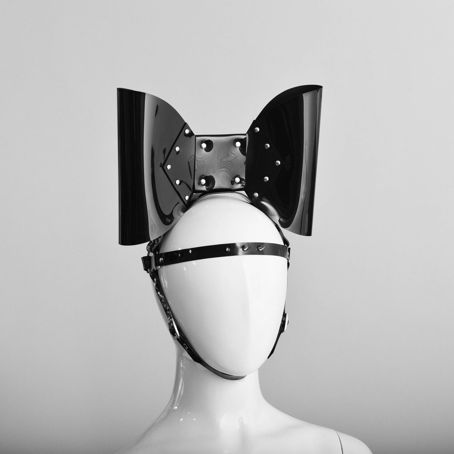 PVC head harness featuring an oversized bow with studs and a spike strap across the forehead.