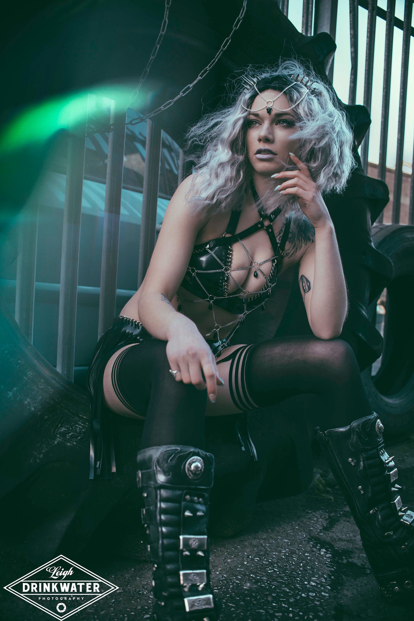 Sitting model wearing black gothic PVC body harness with a network of stainless steel chain and black glass beads.