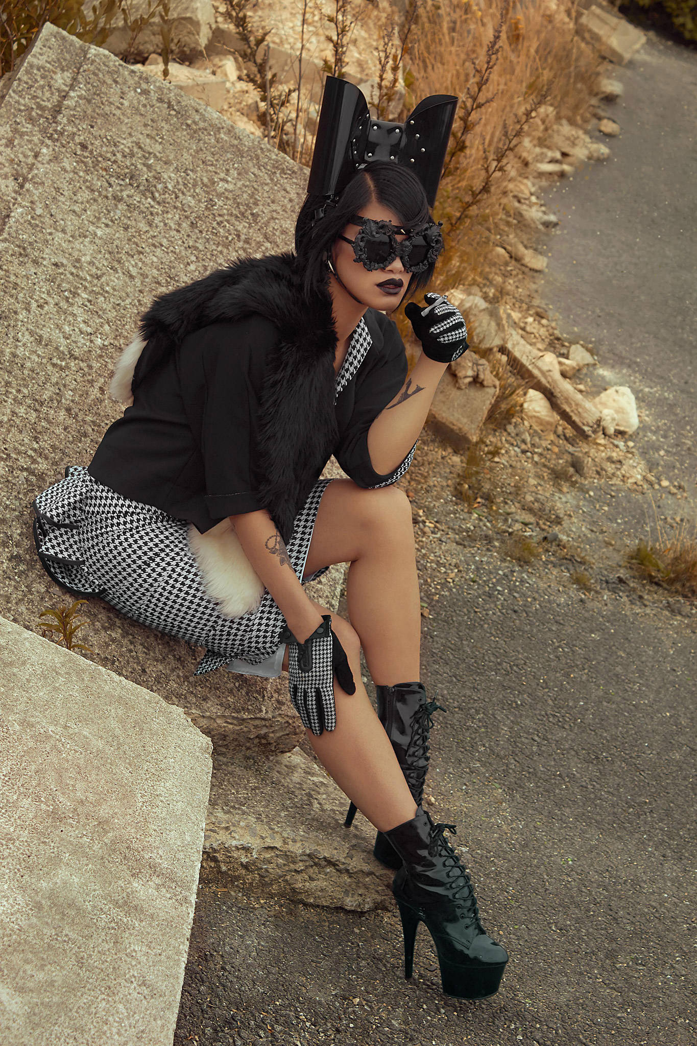 Oversized studded PVC bow headband on a person with black faux-fur and a gingham skirt.