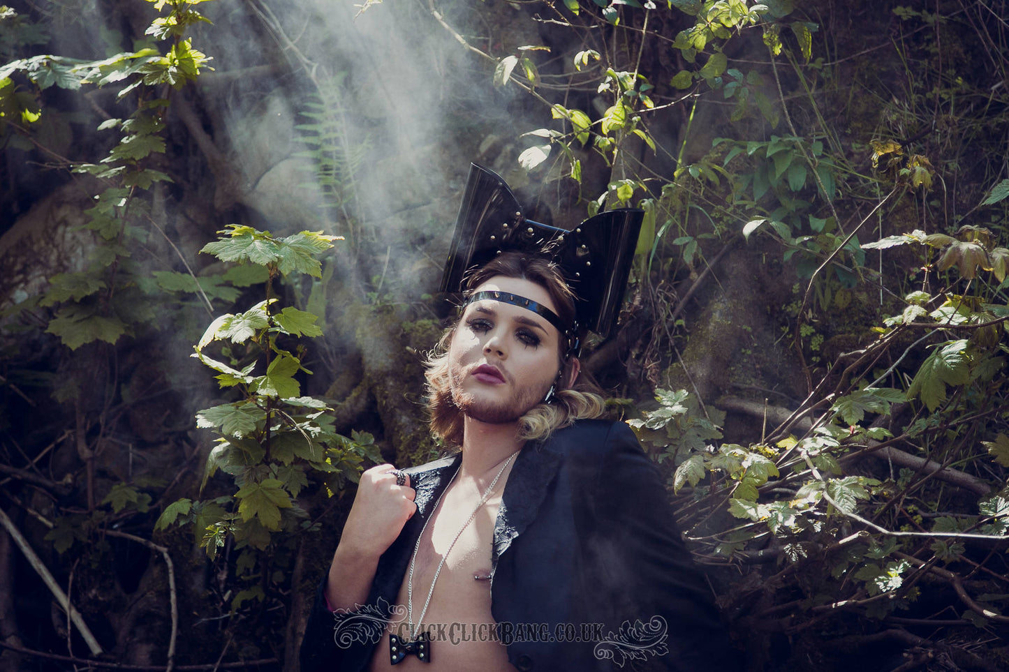 Model wearing a PVC headband featuring an oversized bow with studs and a spiked strap across the forehead.