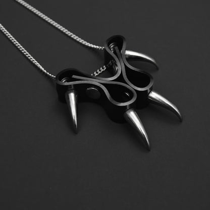Close-up of a black PVC cat claw-style pendant with silver claw spikes, featuring a matching silver chain necklace in an elegant gothic style.