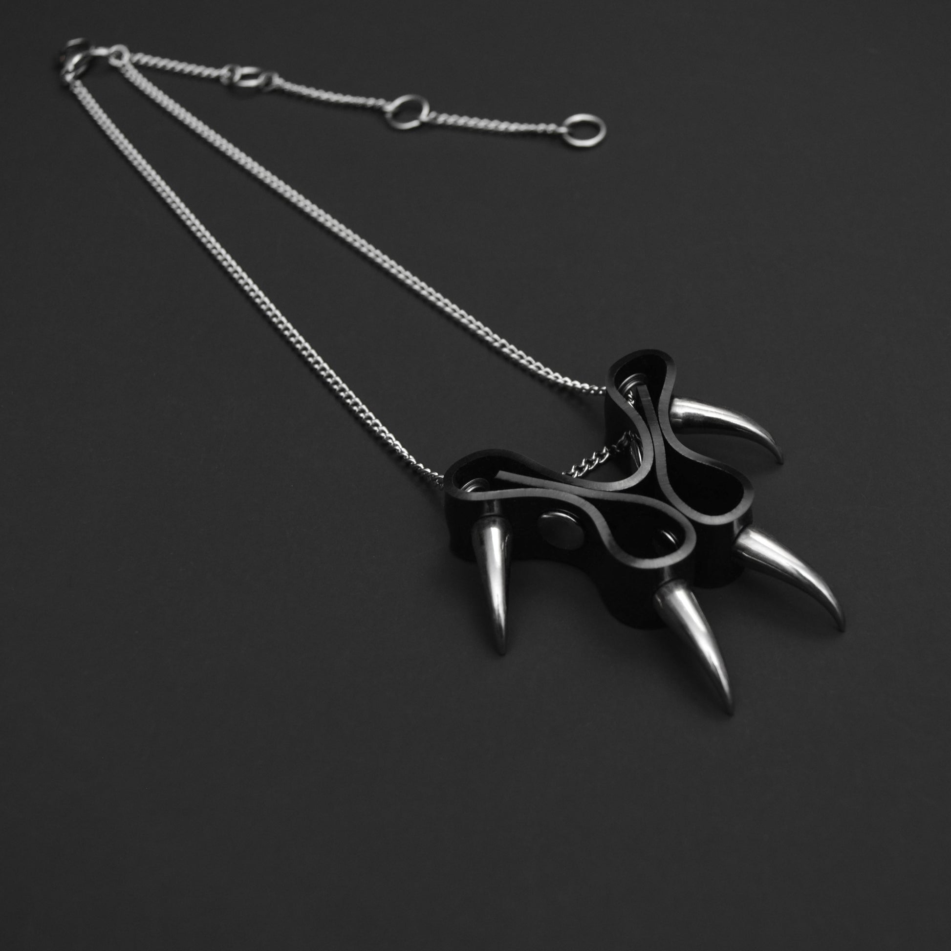 Black PVC cat claw-style pendant with silver claw spikes, on a silver chain necklace with an adjustable extender for customisable fit.