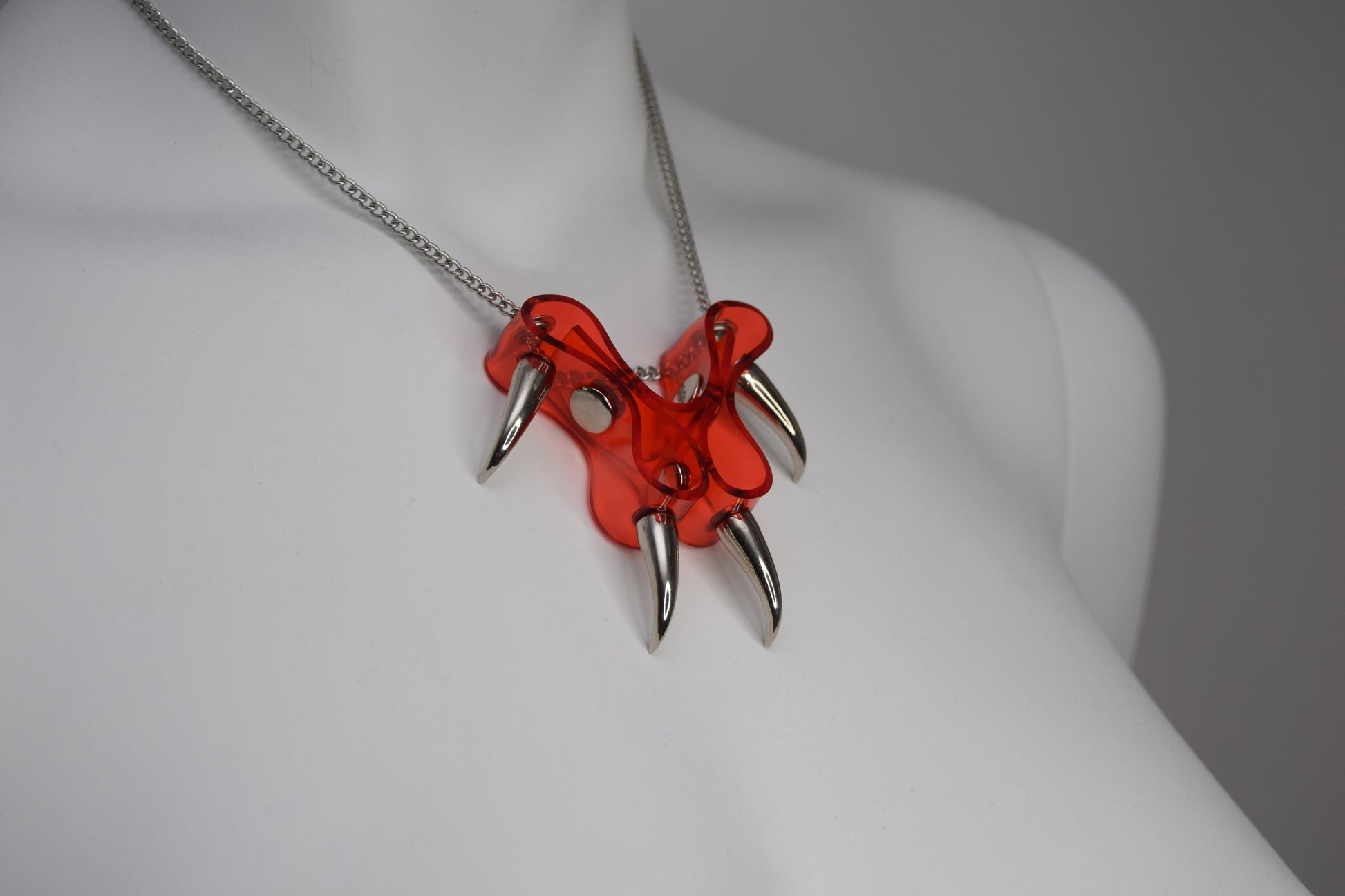 KatzLittleFactory's original CLAWZ necklace showcases a striking combination of red Transparent PVC and silver spikes on a chain.