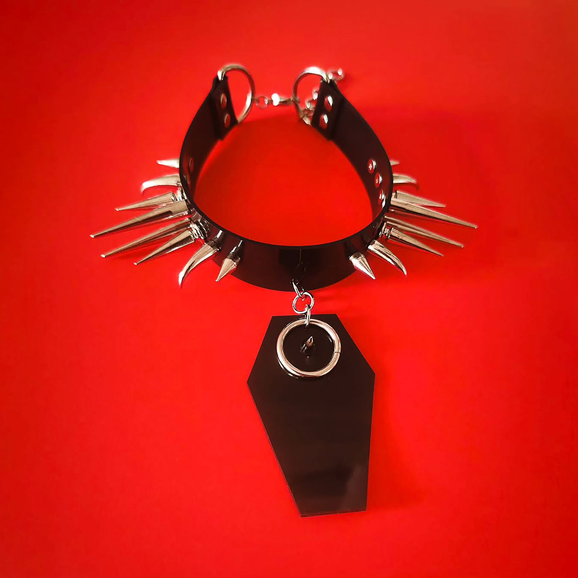Black PVC choker collar with silver spikes and a black coffin-shaped pendant with spike and O-ring detail
