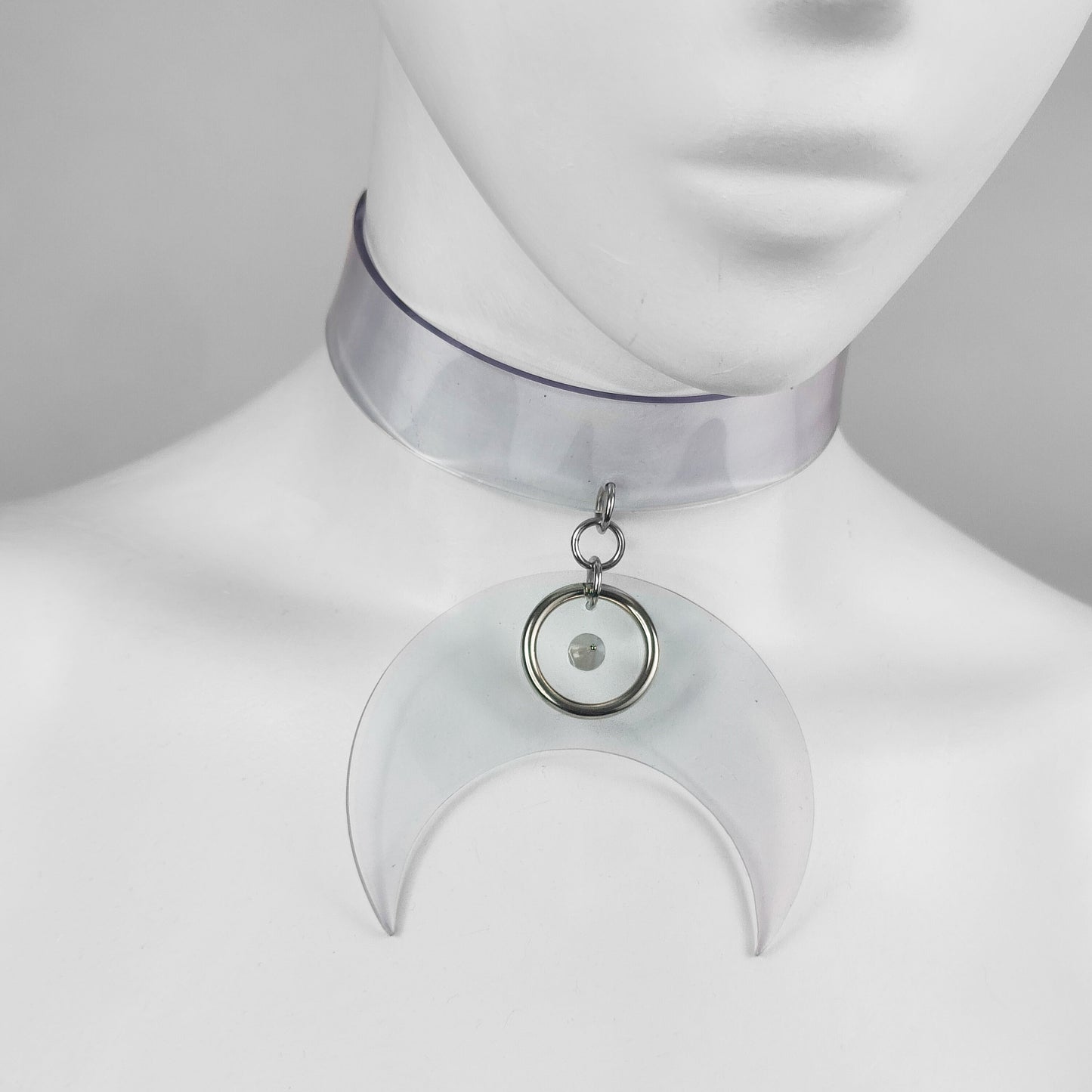 Translucent clear vinyl choker with large crescent moon pendant with metal ring and spike detail.