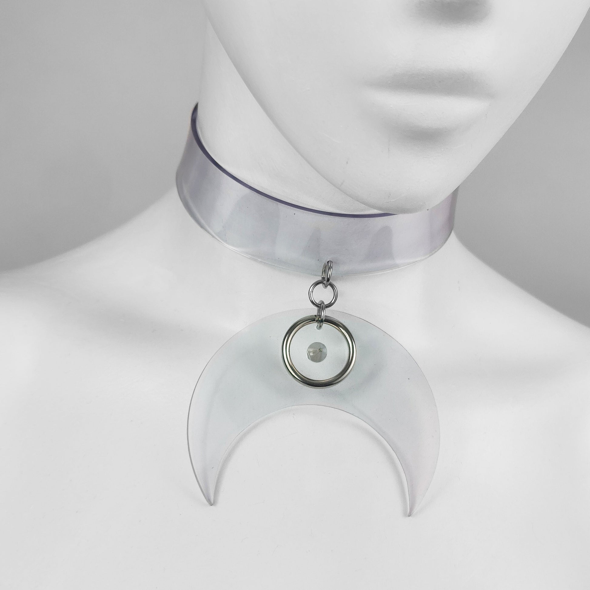Translucent clear vinyl choker with large crescent moon pendant with metal ring and spike detail.