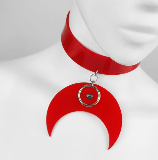 Red retro vinyl choke with large crescent pendant with metal o ring and spike detail.