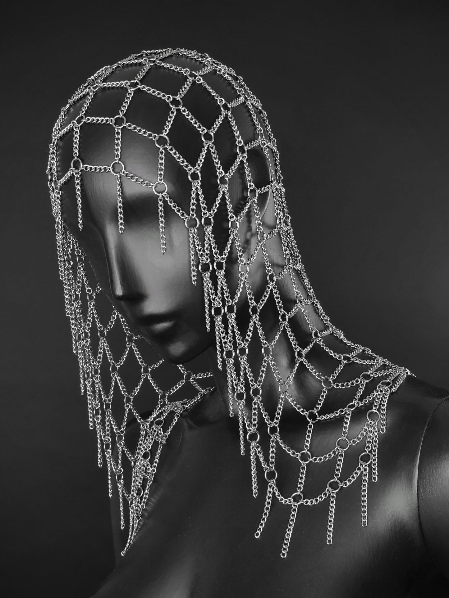 A silver chain mesh head net with dangling chain fringes displayed on a dark mannequin head and shoulders against a dark gray background. Fantasy handmade armour inspired headwear for cosplays and events.