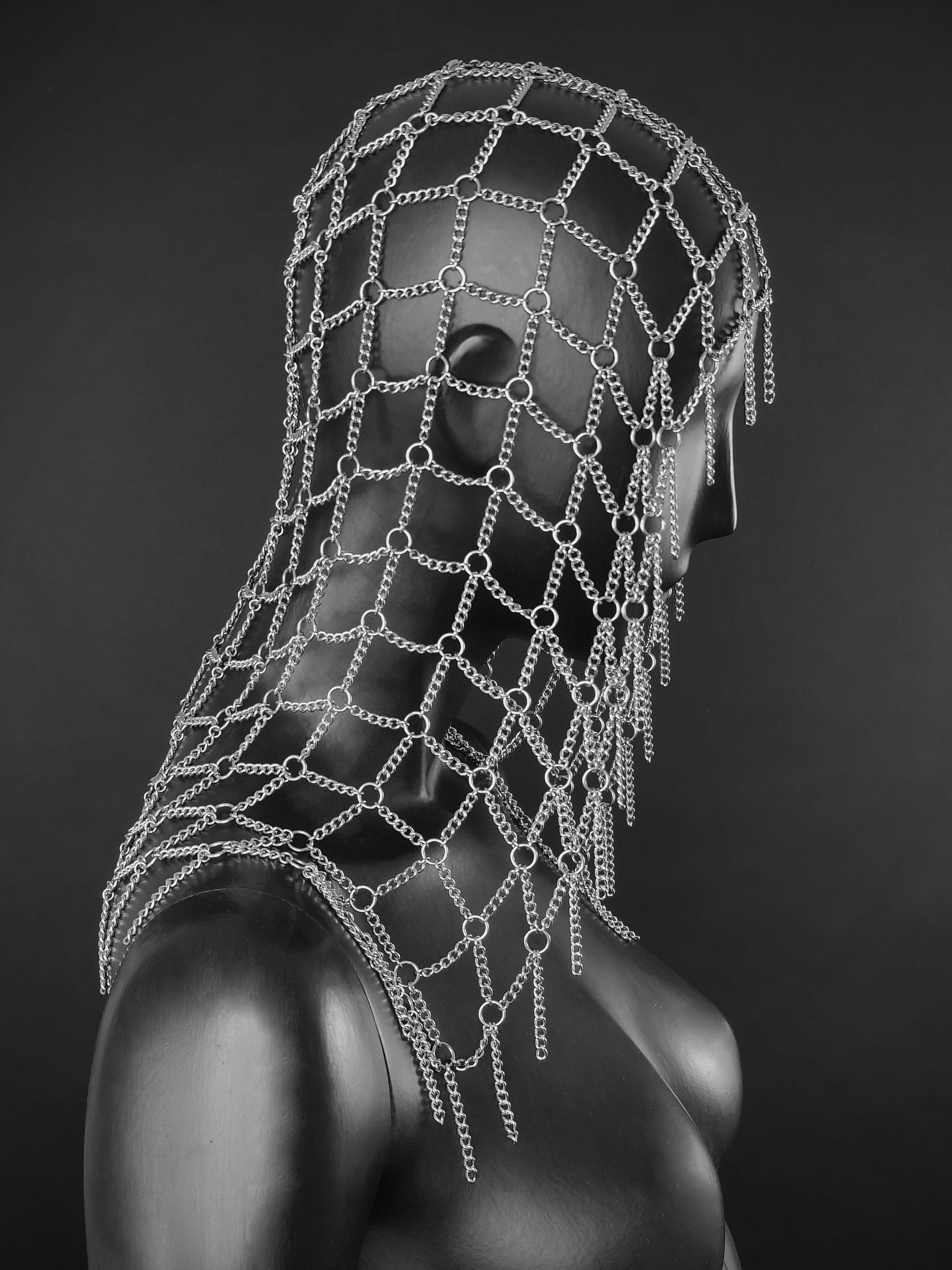 Gothic inspired fantasy headdress made of steel chain mesh on a black display.