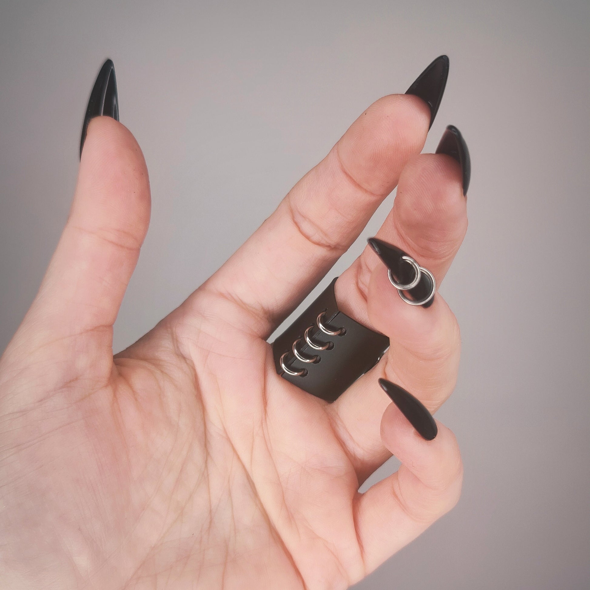 Underside of gothic matte black PVC ring, with a row of jump rings.