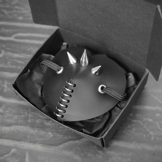 Black heart shape costume eye patch with spike, rings and studs decoration.