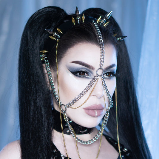Cyber goth model wearing a spike headband headpiece with silver and gold spikes and a heavy chain mask.