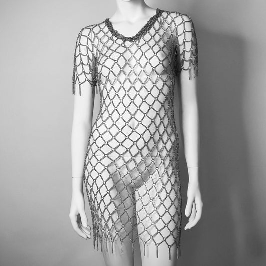 The CRUXXX Dress, featuring an eye-catching geometric pattern with a sqare cross net-like design. The dress is short, with short sleeves and a round neckline, leading down to a fringed hemline.