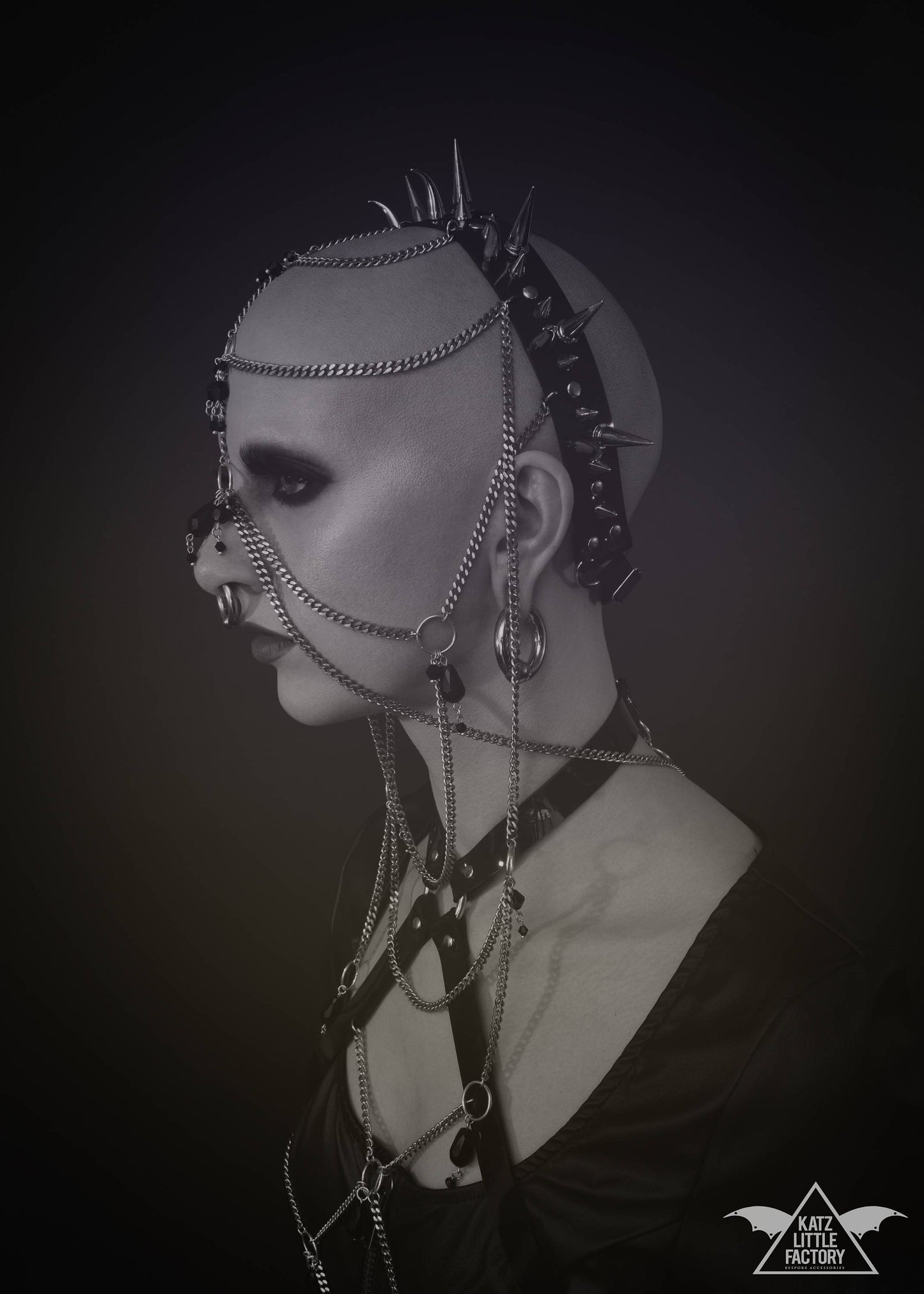Profile of model wearing elaborate gothic headdress with a black PVC headband, clusters of spikes, and stainless steel chains and black glass beads face jewellery.