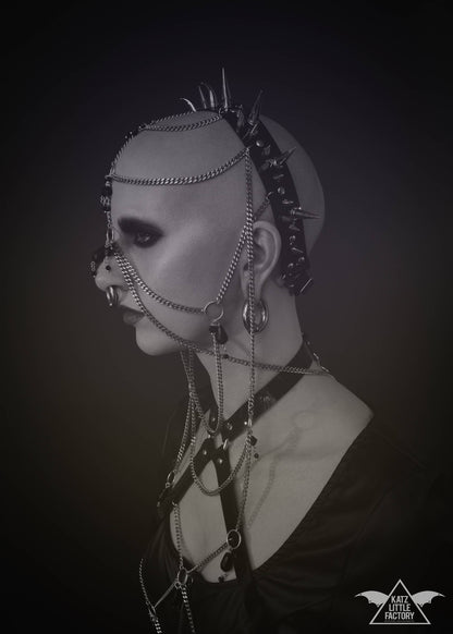 Profile of model wearing elaborate gothic headdress with a black PVC headband, clusters of spikes, and stainless steel chains and black glass beads face jewellery.