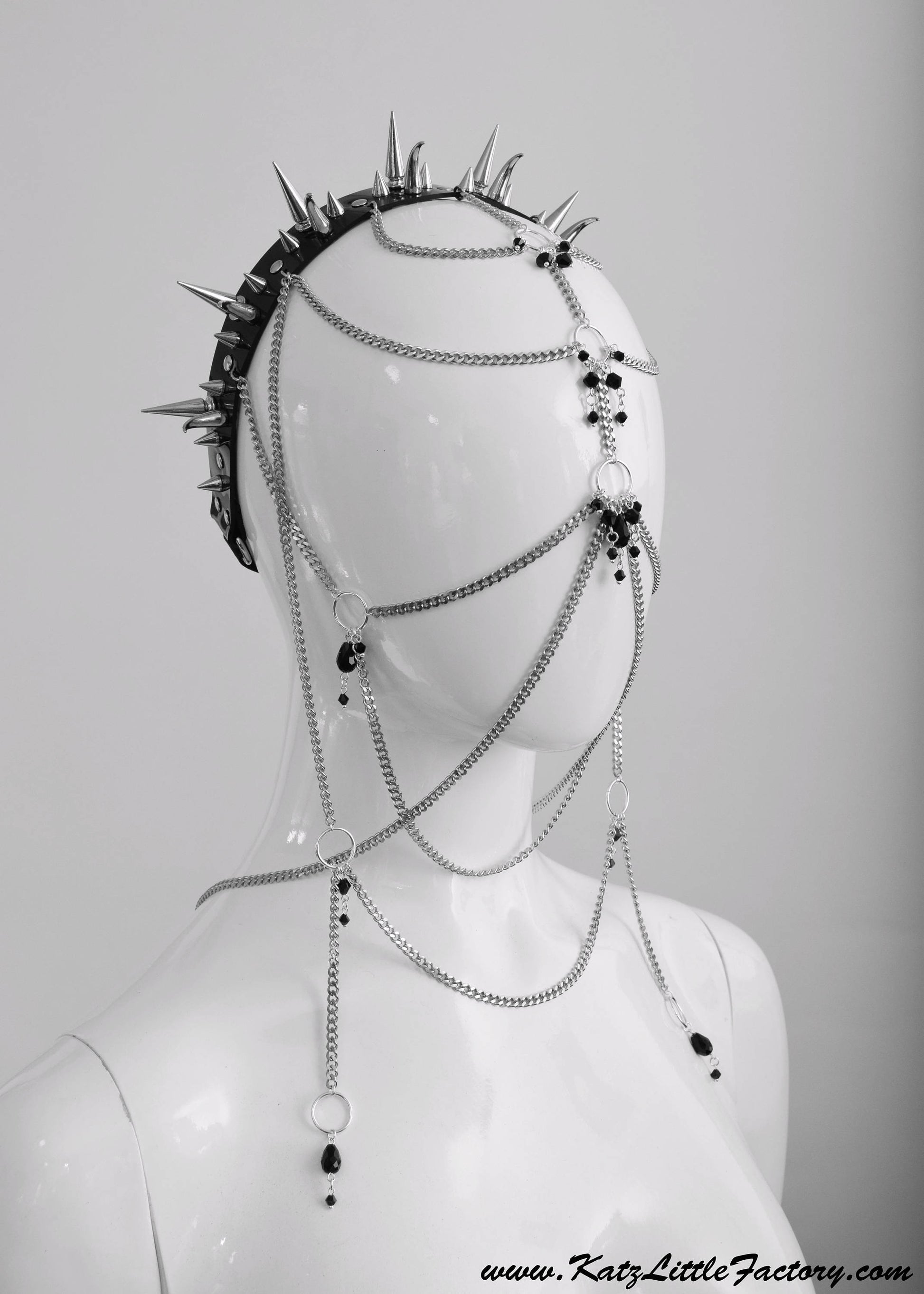 Profile of elaborate gothic headdress with a black PVC headband, clusters of spikes, and stainless steel chains and black glass beads face jewellery.