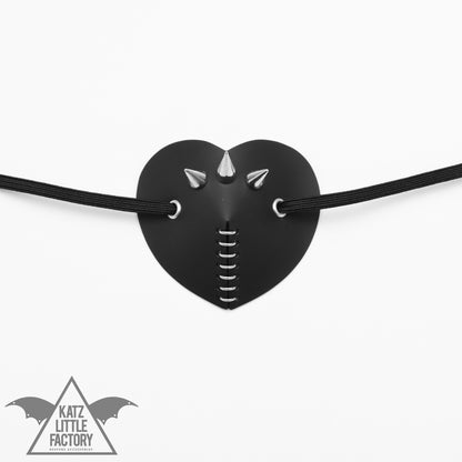 A black heart-shaped eye patch, featuring a cluster of spikes