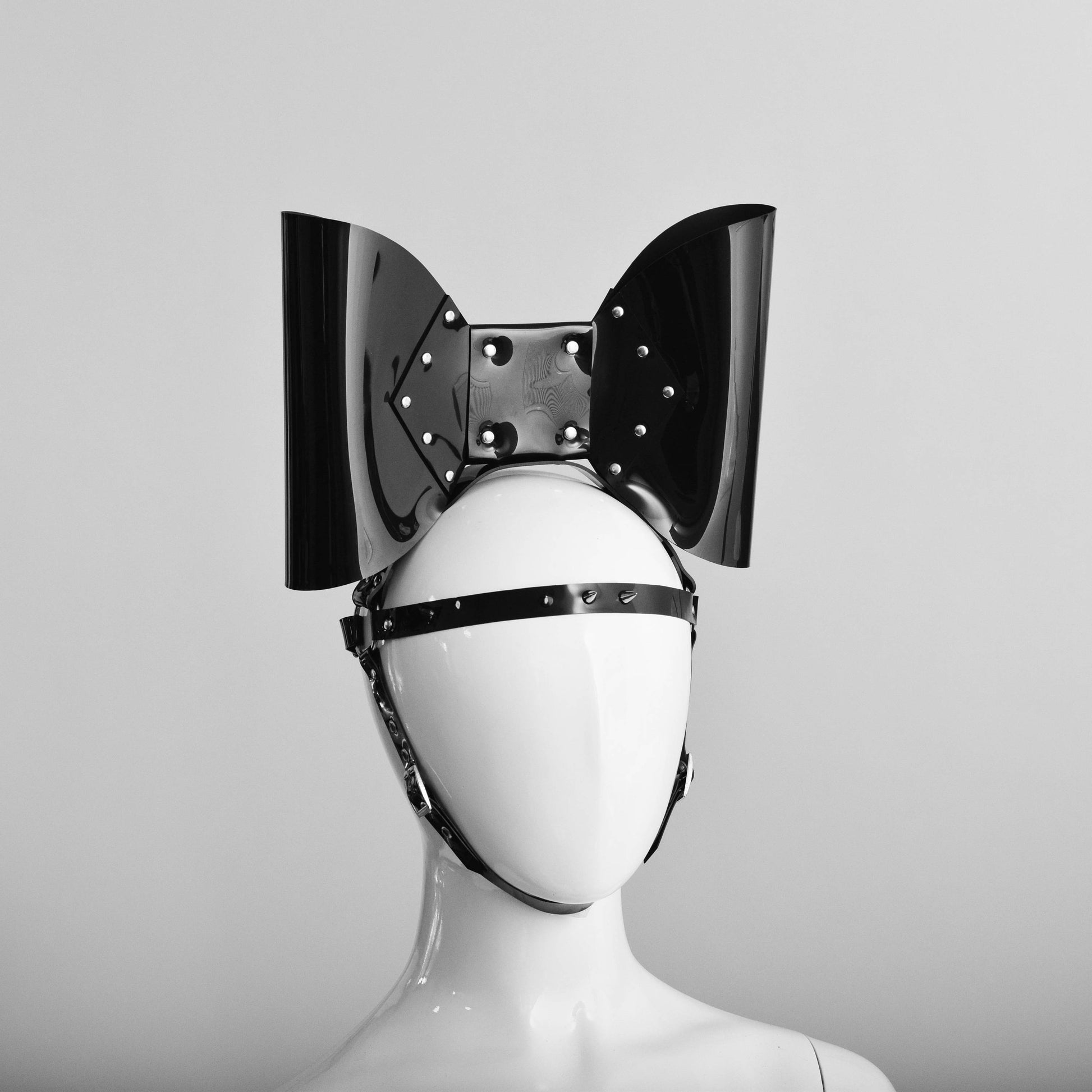 PVC head harness featuring an oversized bow with studs and a spike strap across the forehead.
