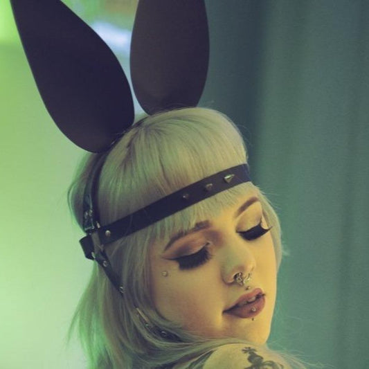 Model wearing a black bunny head harness with large ears, and forehead with spikes.