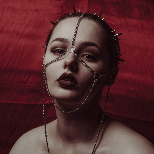 Close-up of a model wearing a gothic black PVC headdress with spike clusters with  stainless steel chain face jewellery.