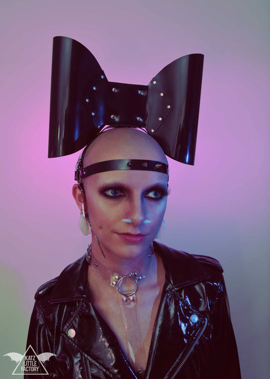 Large, glossy black PVC bow headband with studs and a spiked forehead strap.