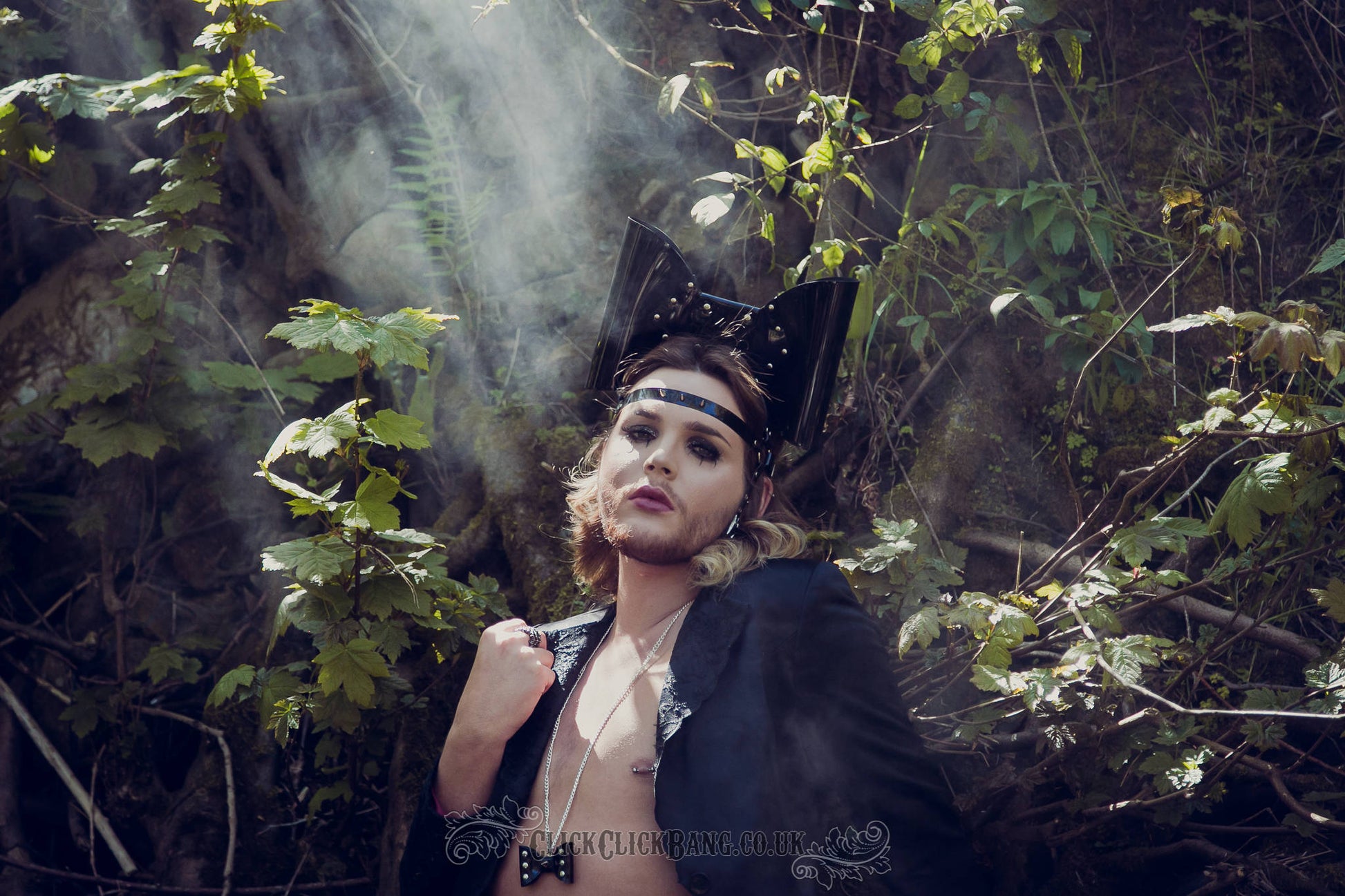 Model wearing a PVC headband featuring an oversized bow with studs and a spiked strap across the forehead.