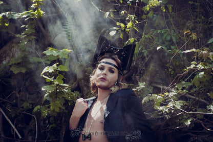 Model wearing a PVC headband featuring an oversized bow with studs and a spiked strap across the forehead.